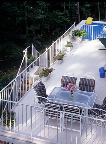 Elevated DeckRite vinyl deck with dining table and a pool in the yard below