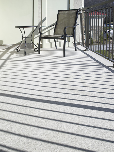 Close view of DeckRite vinyl on a balcony with a chair and metal railing