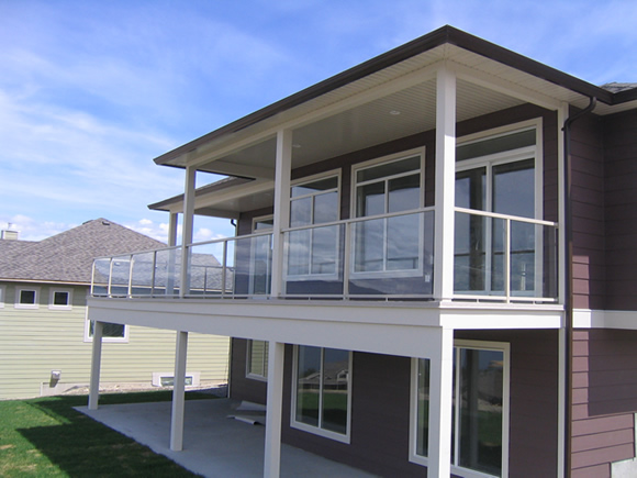 Elevated residential balcony with a glass rail over a driveway
