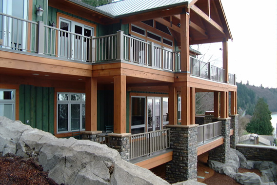 Timber waterfront home with upper and lower decks and metal rails