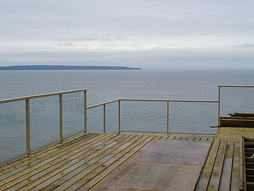Open waterfront deck with a glass rail facing the horizon
